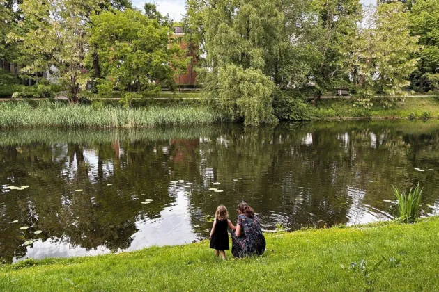 Woman and child by a pond in a park.