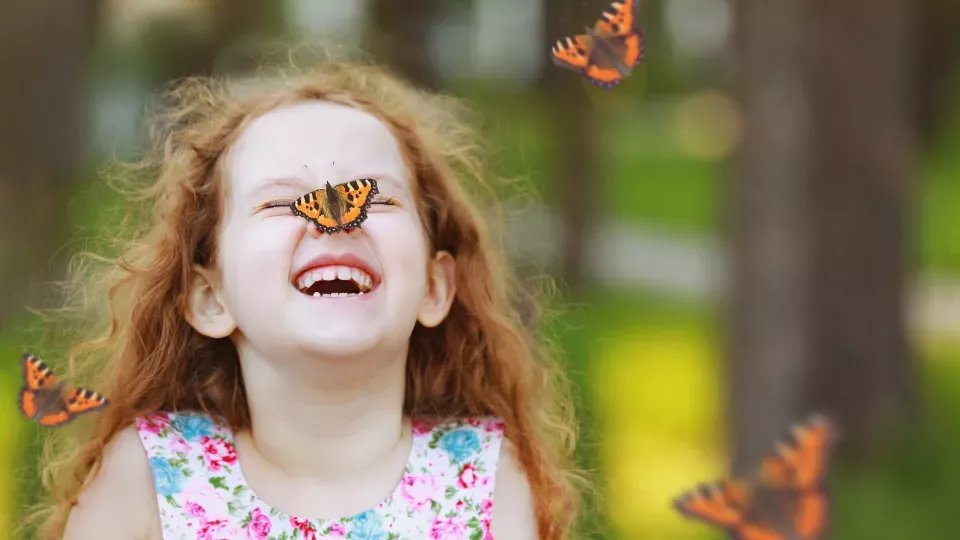A girl with a butterfly on her nose. Photo.