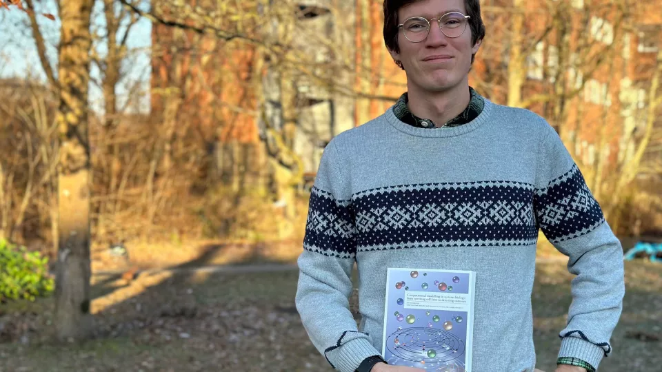 Emil outdoors with a grey sweater. Photo.