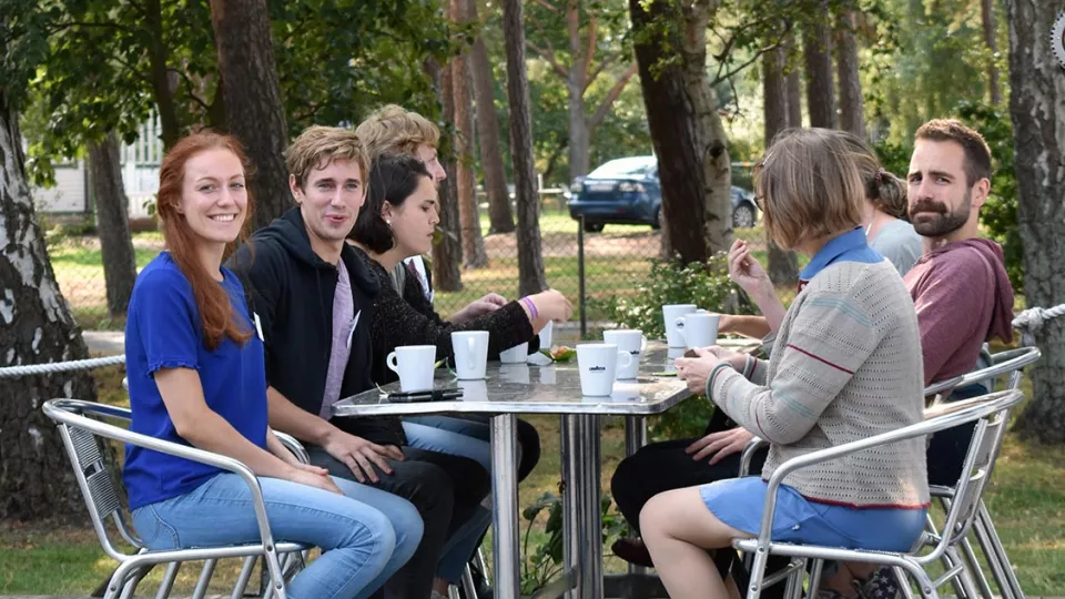 Participants sitting at a table outside, drinking coffee. Photo.