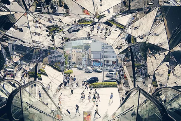 image of a city street in background, reflected in a mirrored escelator tunnel in the foreground.