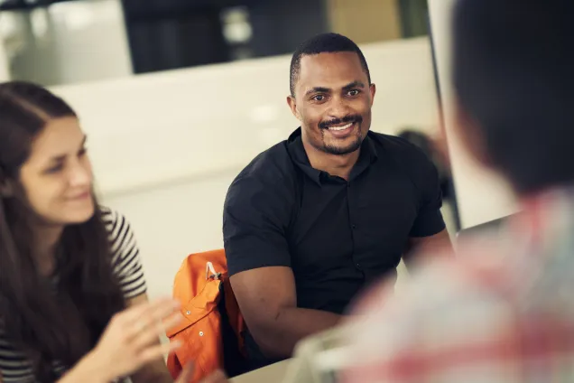 Tre personer som sitter och pratar. Foto.