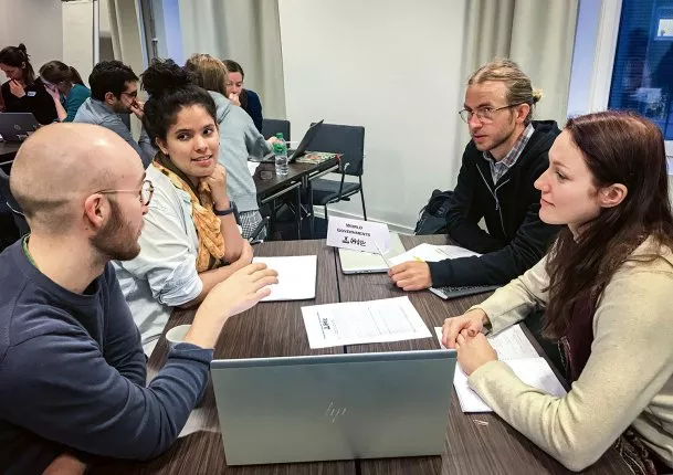 Fyra personer sitter runt ett bord och pratar och simulerar att de klimatförhandlar. Bild: Stina Johannesson.